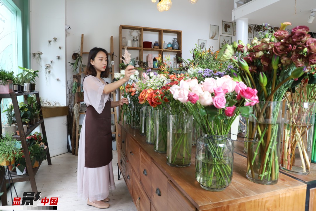 王黎媛是一名河南姑娘，在昆明念完大學(xué)后，就再也舍不下春城的藍(lán)天陽光、青山碧水，更舍不下這里的四時繁花，于是就干脆留了下來，成了一名媒體人。2017年的時候又毅然辭去工作，創(chuàng)業(yè)開起了花店，成了都市里的一名“花房姑娘”。圖為王黎媛在自己的花店中整理鮮花。新華網(wǎng) 周亞平/攝 念新洪/文